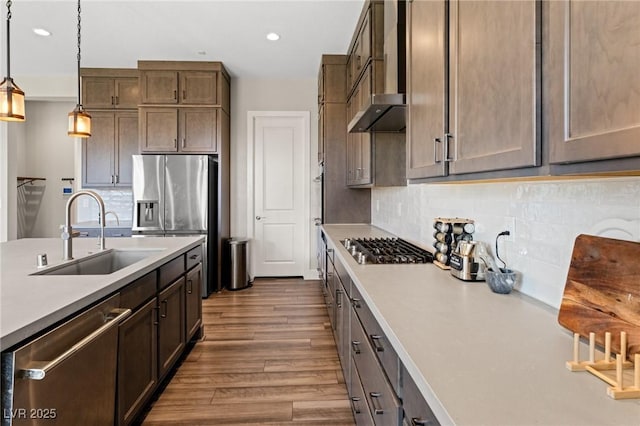 kitchen featuring appliances with stainless steel finishes, wood finished floors, light countertops, pendant lighting, and a sink