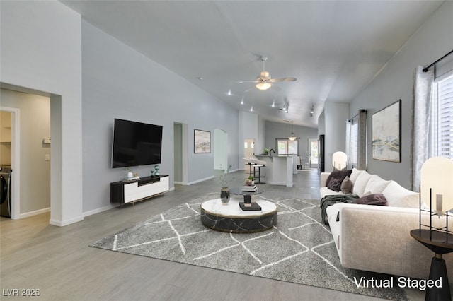 living room featuring washer / dryer, vaulted ceiling, ceiling fan, and hardwood / wood-style floors