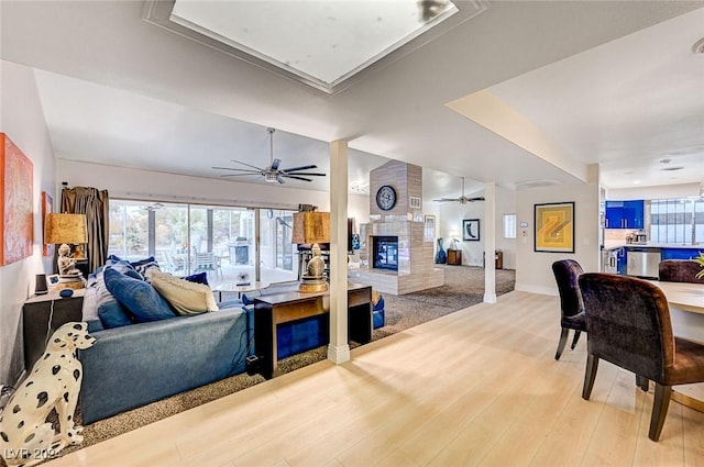 living room with hardwood / wood-style flooring, ceiling fan, a fireplace, and vaulted ceiling