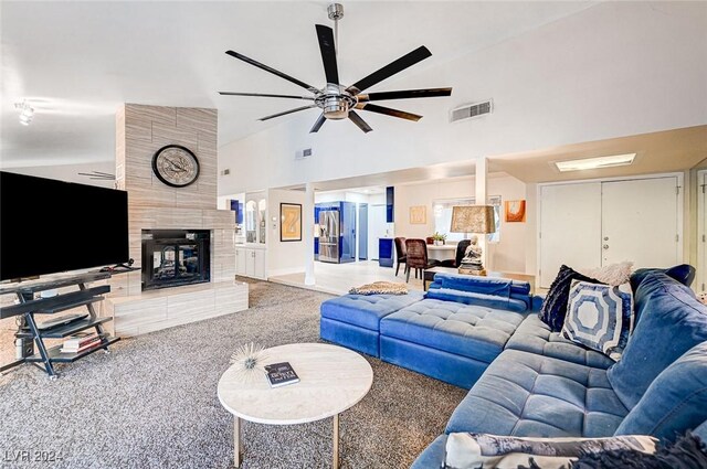 carpeted living room with high vaulted ceiling, ceiling fan, and a tiled fireplace