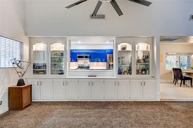 bar featuring white cabinets, appliances with stainless steel finishes, light colored carpet, and ceiling fan