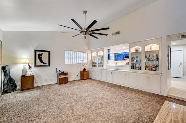 unfurnished living room with light colored carpet, high vaulted ceiling, and ceiling fan