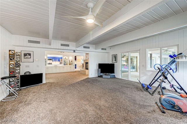 exercise room with carpet floors, ceiling fan, and wood walls