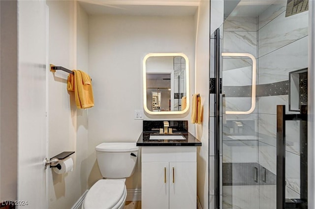 bathroom with a shower with door, vanity, and toilet