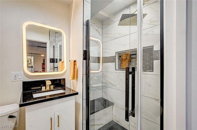 bathroom featuring a shower with door, vanity, and toilet