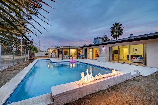 pool at dusk with central air condition unit and a patio area