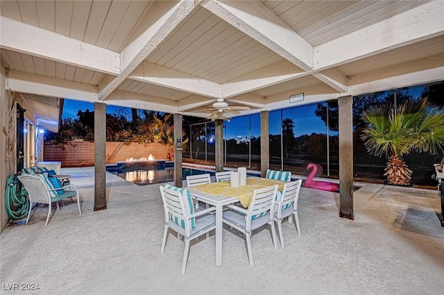 patio terrace at dusk with a fenced in pool and ceiling fan