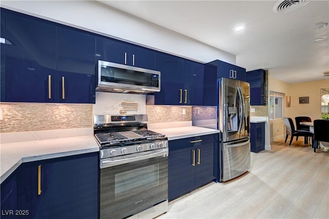 kitchen featuring visible vents, stainless steel appliances, blue cabinets, and light countertops
