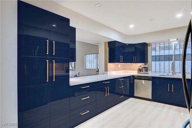 kitchen featuring stainless steel dishwasher, light countertops, blue cabinetry, and a wealth of natural light