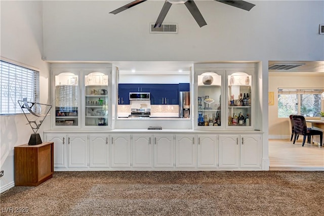 bar featuring visible vents, stainless steel appliances, carpet, and a ceiling fan