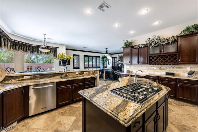 kitchen featuring stainless steel appliances, ceiling fan, sink, a large island with sink, and hanging light fixtures