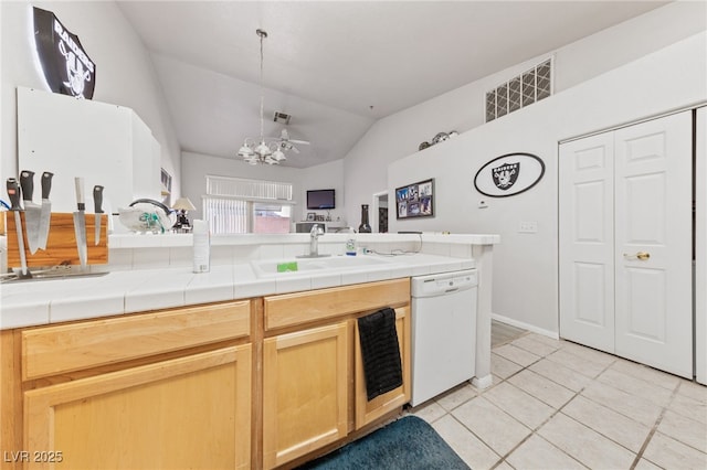 kitchen with tile countertops, white dishwasher, sink, vaulted ceiling, and light tile patterned floors