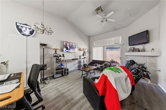 living room featuring wood-type flooring, ceiling fan with notable chandelier, and vaulted ceiling