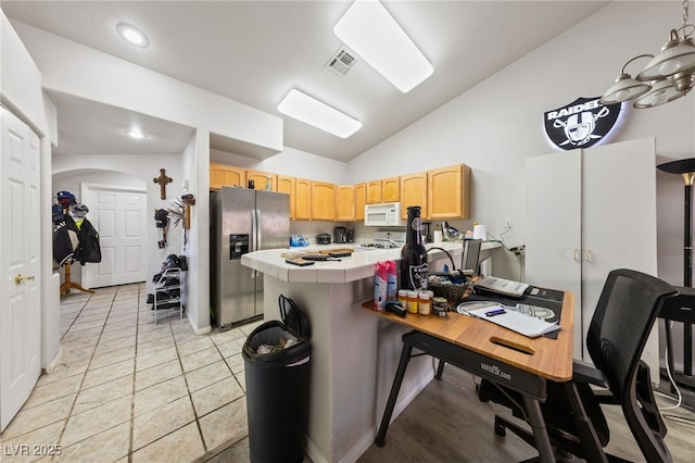 kitchen featuring vaulted ceiling, stainless steel fridge, light tile patterned floors, tile counters, and kitchen peninsula