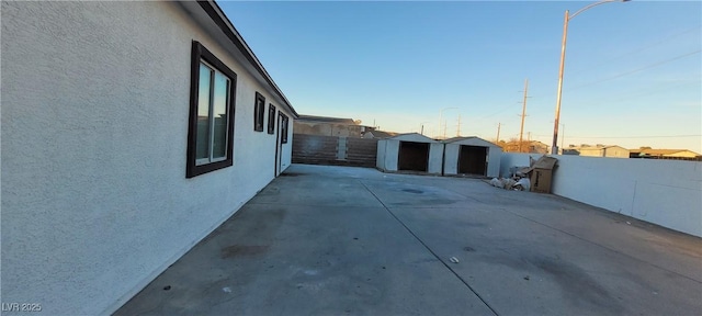 property exterior at dusk with a patio area and a storage shed