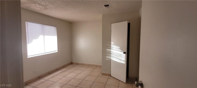 tiled empty room with a textured ceiling