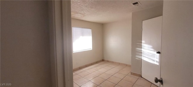 tiled empty room featuring a textured ceiling