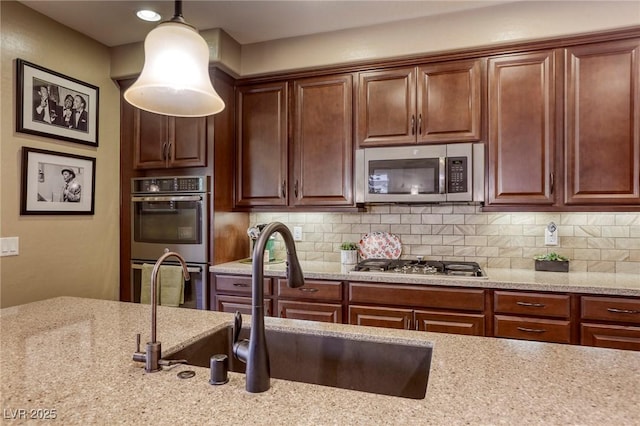 kitchen featuring light stone countertops, hanging light fixtures, appliances with stainless steel finishes, and tasteful backsplash