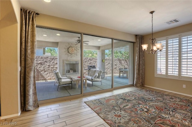 entryway featuring hardwood / wood-style floors, ceiling fan with notable chandelier, and a healthy amount of sunlight