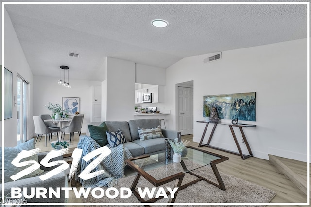 living room with lofted ceiling, visible vents, light wood-style floors, a textured ceiling, and baseboards