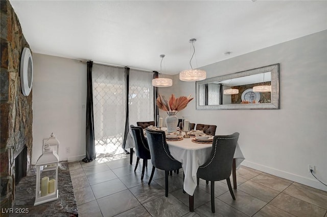 tiled dining area with a stone fireplace