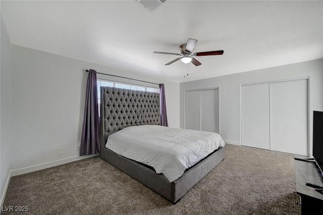 bedroom with carpet flooring, ceiling fan, and two closets