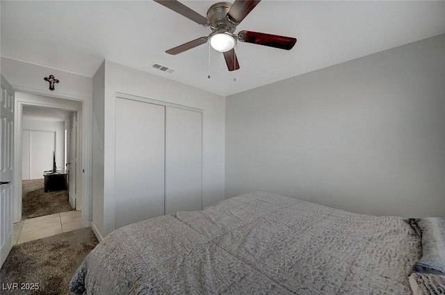 carpeted bedroom with ceiling fan and a closet