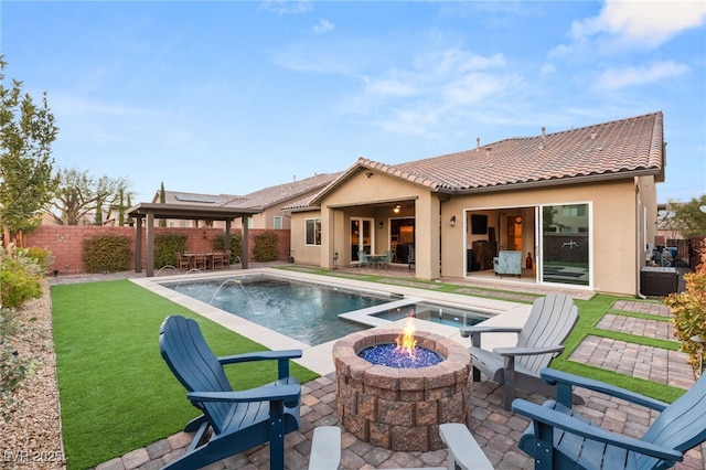 back of house with a fenced in pool, pool water feature, a patio area, and a fire pit