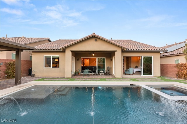 rear view of property with a patio, pool water feature, and a pool with hot tub