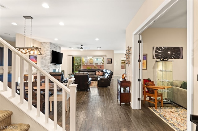 stairway featuring wood-type flooring, a stone fireplace, and ceiling fan