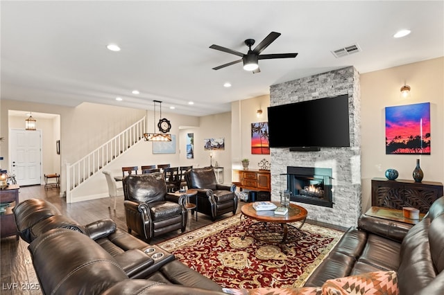 living room featuring a stone fireplace, ceiling fan, and hardwood / wood-style flooring