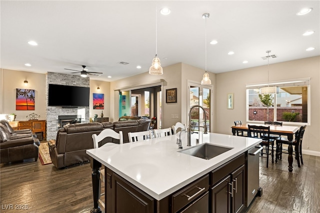 kitchen featuring hanging light fixtures, an island with sink, sink, and ceiling fan