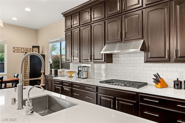 kitchen featuring stainless steel gas stovetop, sink, dark brown cabinetry, and decorative backsplash