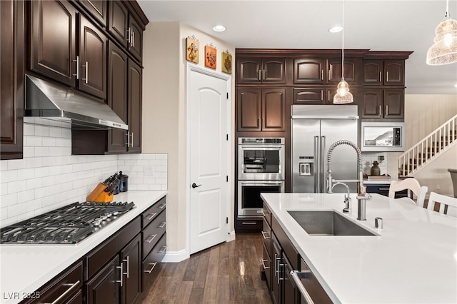 kitchen with appliances with stainless steel finishes, dark hardwood / wood-style floors, tasteful backsplash, sink, and hanging light fixtures