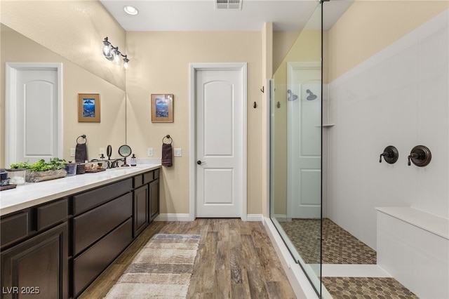 bathroom with vanity, hardwood / wood-style floors, and tiled shower