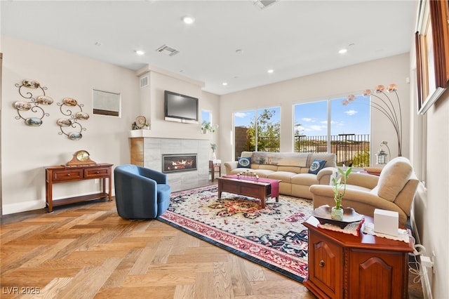 living room featuring a tile fireplace and light parquet floors