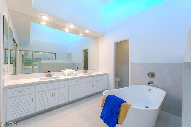 full bathroom featuring tile walls, toilet, vanity, and shower with separate bathtub