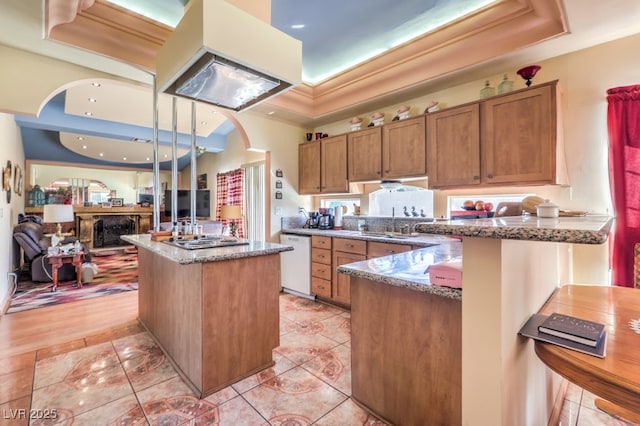 kitchen with white dishwasher, a center island, light tile patterned floors, and dark stone counters