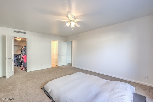 bedroom featuring a walk in closet, ceiling fan, a closet, and light colored carpet