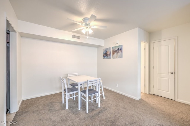 dining space with ceiling fan and light colored carpet