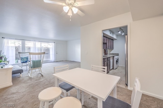 dining room featuring ceiling fan, washer / dryer, and light colored carpet