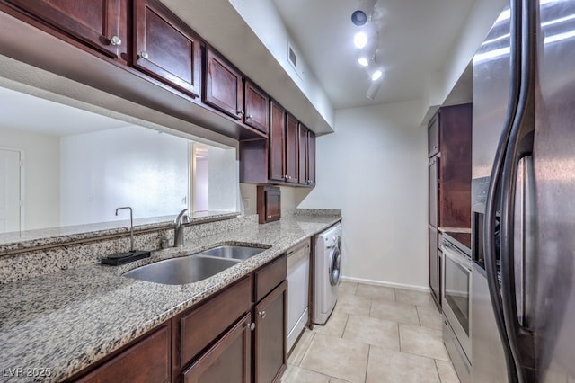 kitchen featuring sink, stainless steel fridge with ice dispenser, light stone counters, washer / clothes dryer, and light tile patterned floors