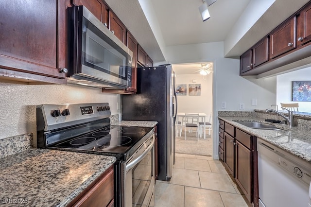 kitchen featuring sink, ceiling fan, light stone countertops, appliances with stainless steel finishes, and light tile patterned flooring