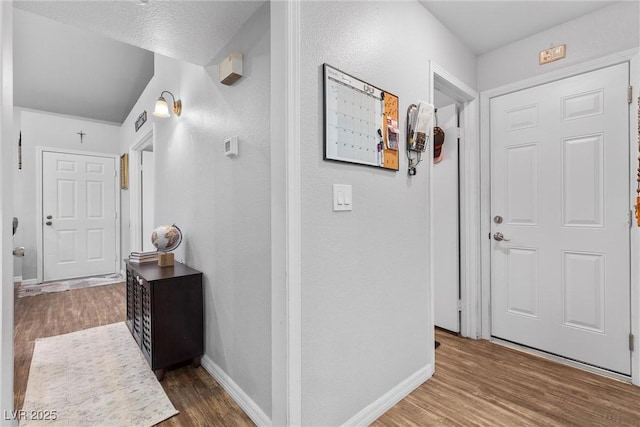 corridor with a textured ceiling and hardwood / wood-style floors