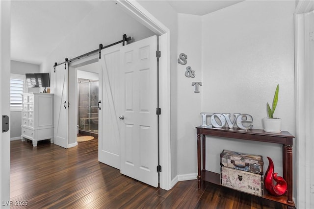 corridor featuring vaulted ceiling, a barn door, and dark hardwood / wood-style floors