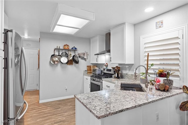 kitchen with stainless steel appliances, kitchen peninsula, wall chimney exhaust hood, sink, and white cabinetry