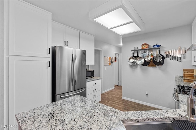 kitchen featuring stainless steel appliances, white cabinets, sink, and light stone countertops