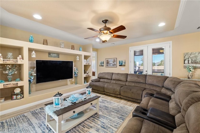 living room featuring ceiling fan, french doors, light hardwood / wood-style floors, and built in features