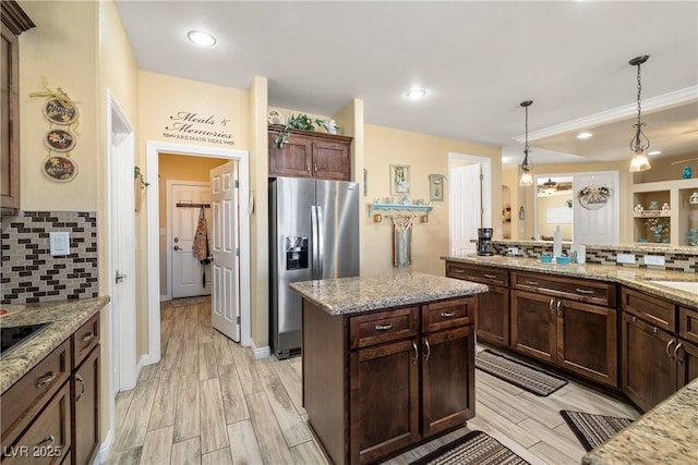 kitchen featuring stainless steel fridge with ice dispenser, tasteful backsplash, light stone counters, and hanging light fixtures