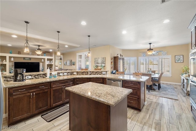 kitchen with a center island, sink, light stone counters, kitchen peninsula, and pendant lighting